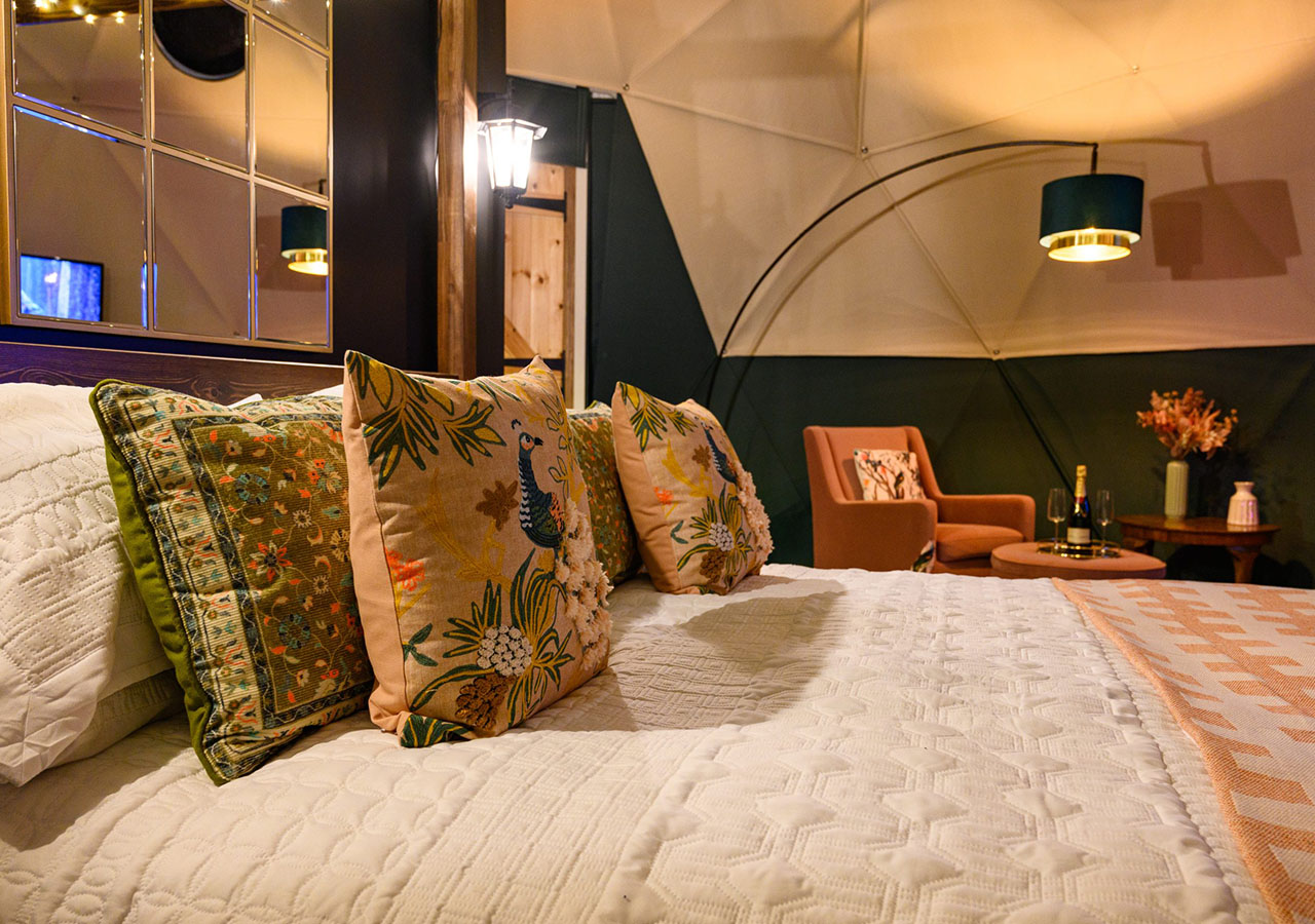 Plump cushions on a bed in Hillside Haven glamping dome at Coorie Retreats