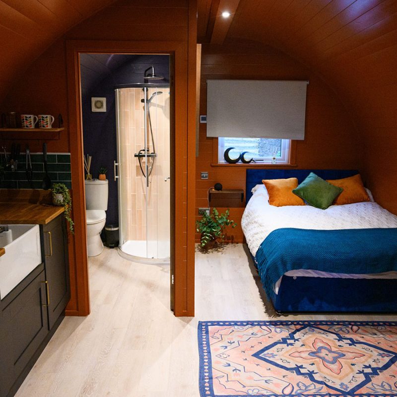 The bed kitchen and bathroom inside the Great Glen glamping pod at Coorie Retreats