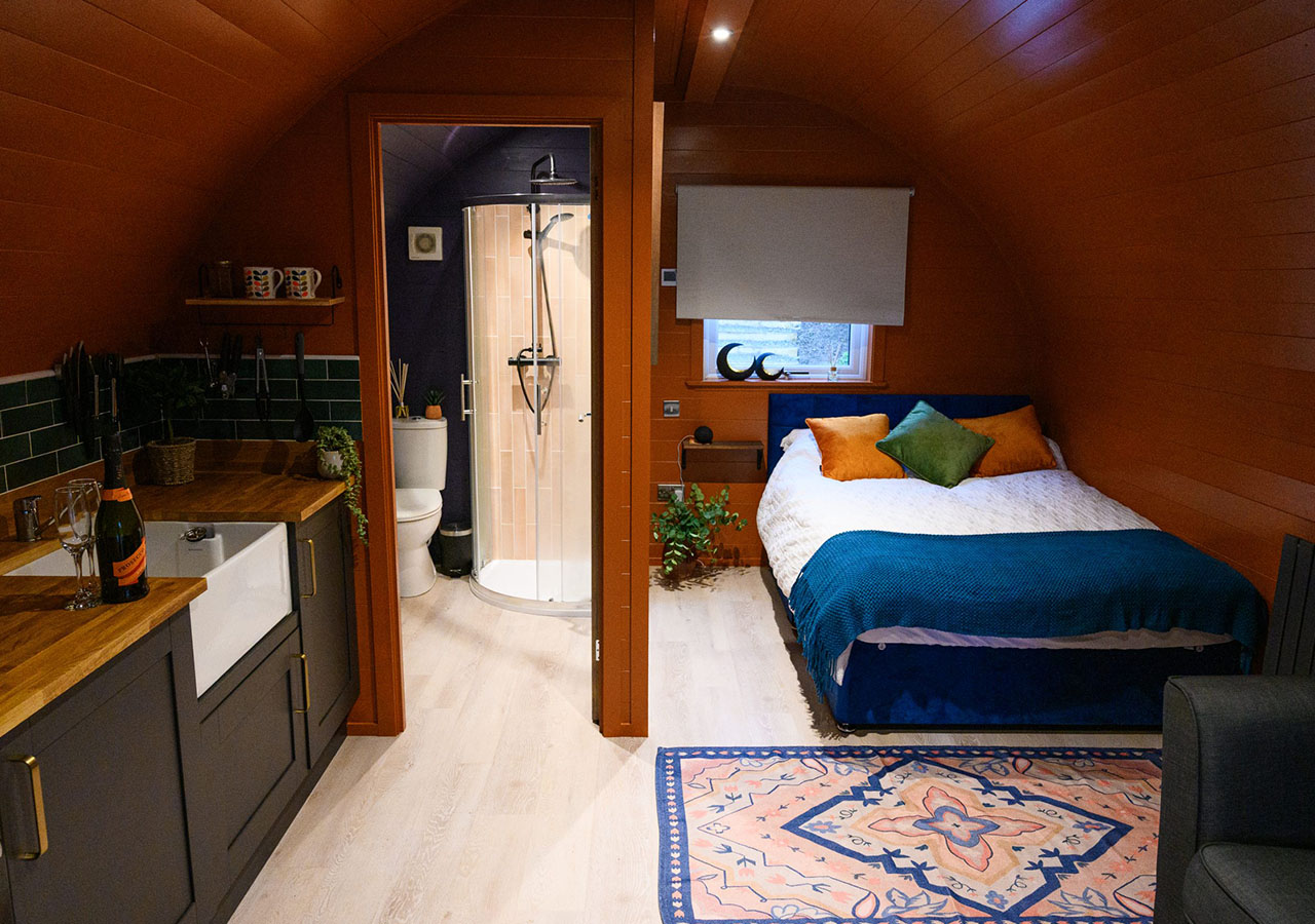 The bed kitchen and bathroom inside the Great Glen glamping pod at Coorie Retreats