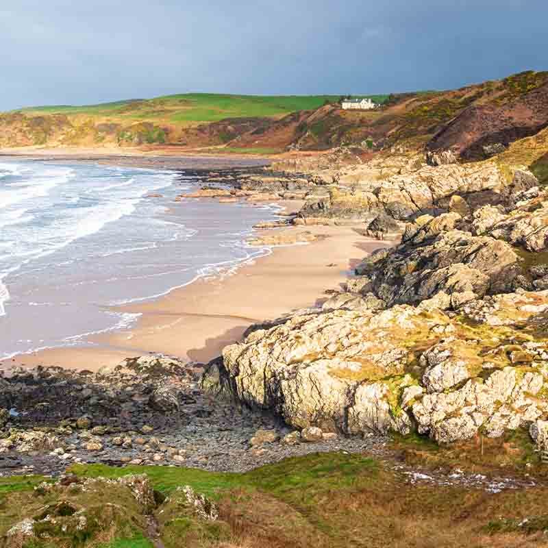 A wide open beach with crashing waves and sand dunes in Dumfries and Galloway.