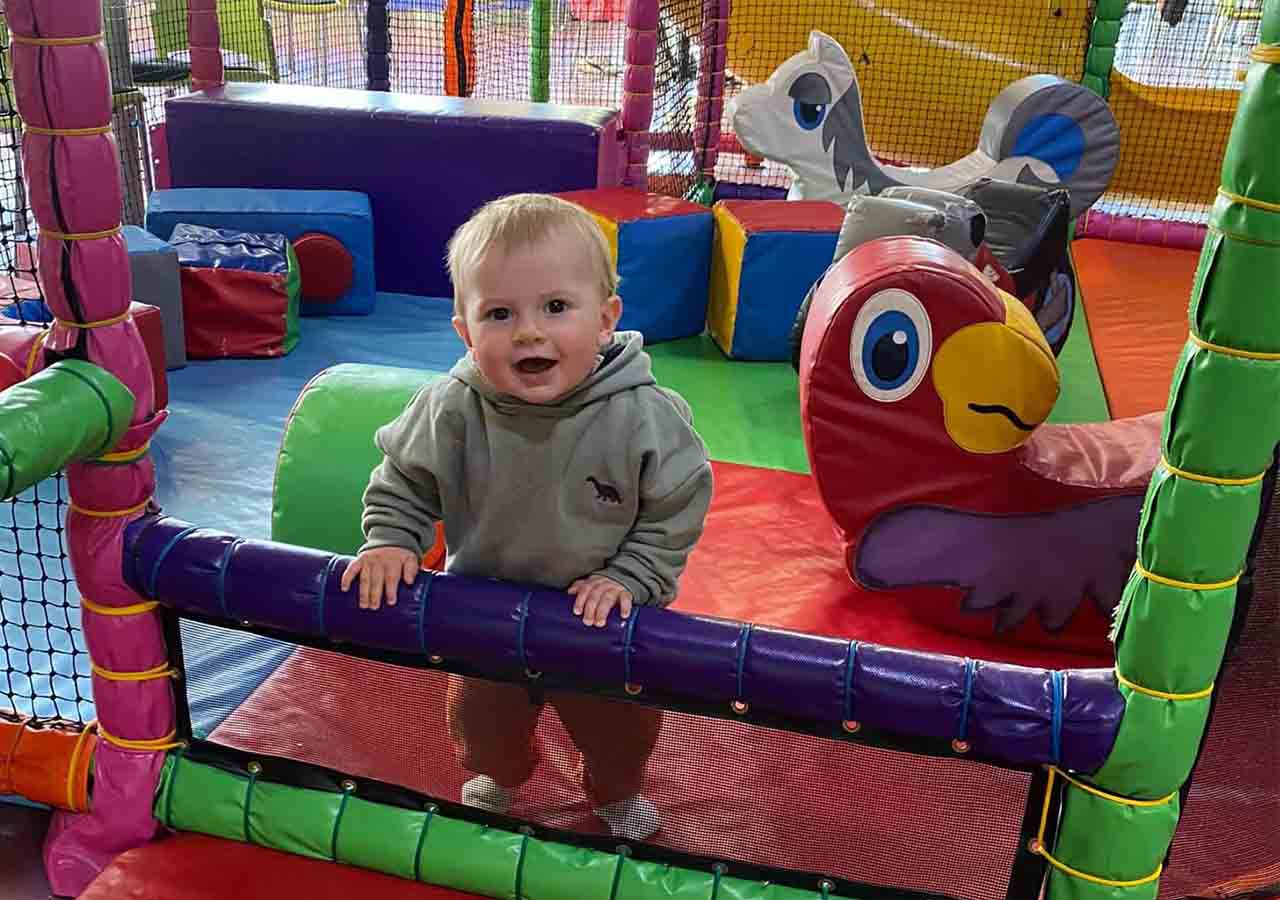 A child in soft play with a toy parrot.